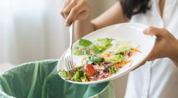 Person scraping food off their plate into bin 