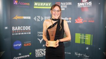 Lucy Beardsmore smiling holding award trophy.