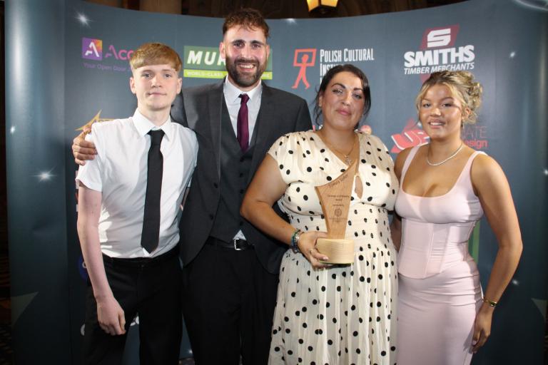 Ezmay Usher's friends and family smiling holding her awards trophy.