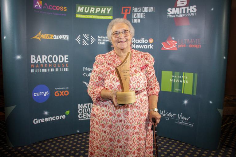 Gilly Hagen smiling holding award trophy.