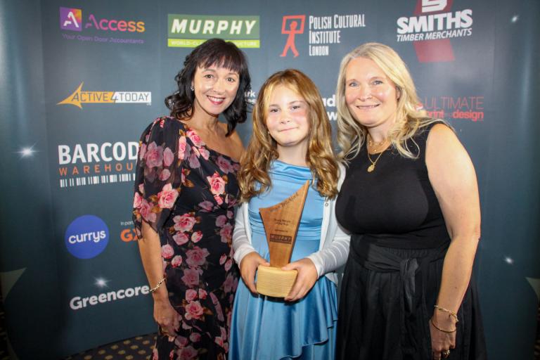 Grace Britchford and family smiling holding award trophy.
