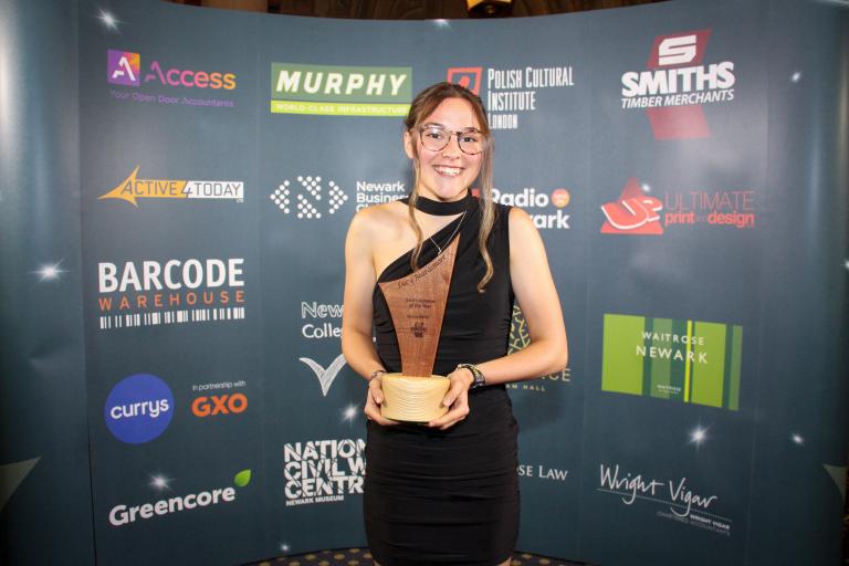 Lucy Beardsmore smiling holding award trophy.